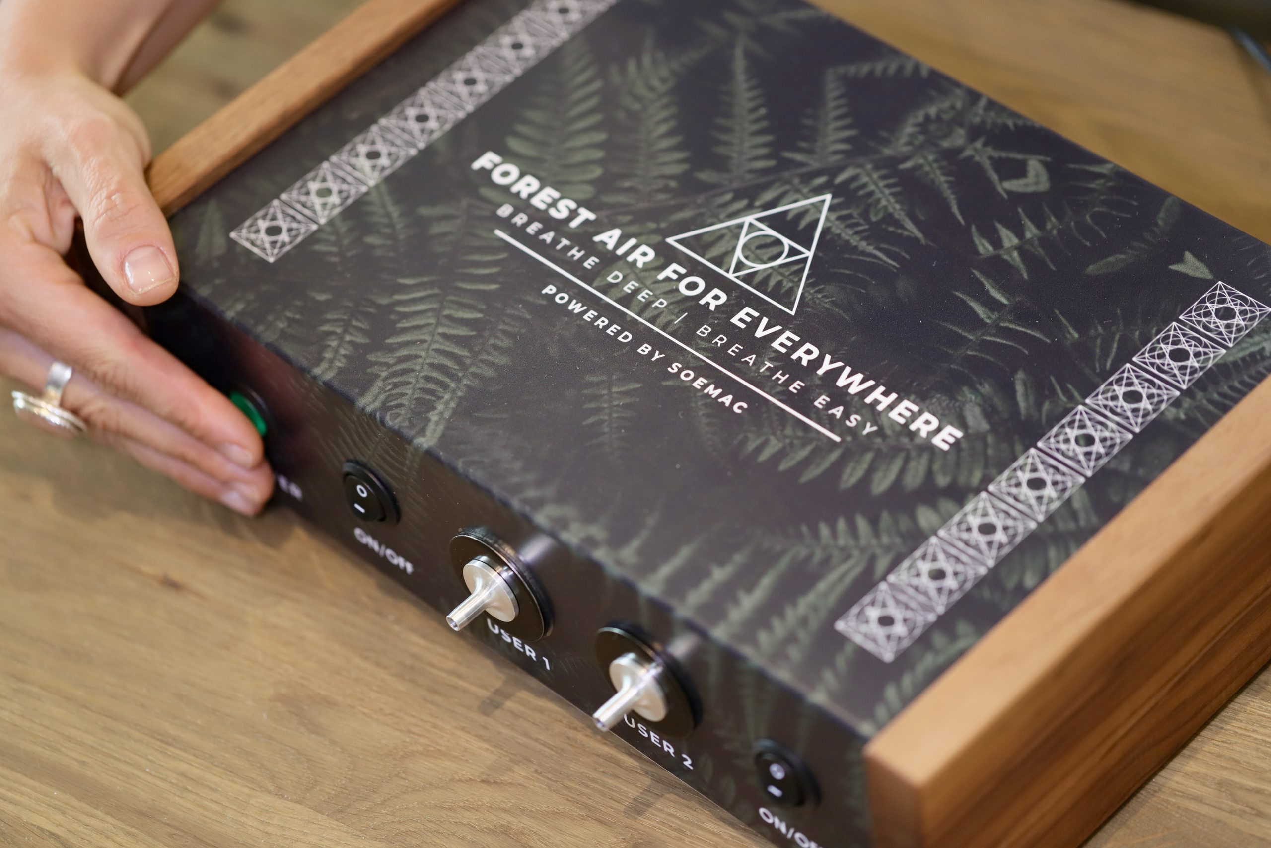 Hand on the control panel of the Forest Air Pro on a wooden table